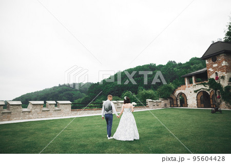Happy wedding couple walking in a botanical park Happy wedding couple walking in a botanical park 95604428