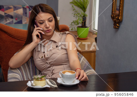 Beautiful serious woman talks on mobile phone in cafe. Portrait picture 95605846