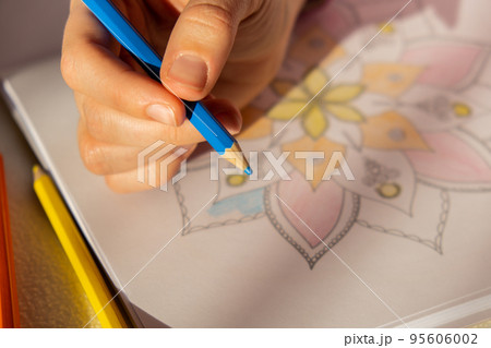 Female painting mandalas antistress page to combat stress. Relaxing hobby mental wellbeing and art therapy. Woman paints sketch, meditative process of coloring pages. Self expression by art Female painting mandalas antistress page to combat stress. Relaxing hobby mental wellbeing and art therapy. Woman paints sketch, meditative process of coloring pages. Self expression by art 95606002