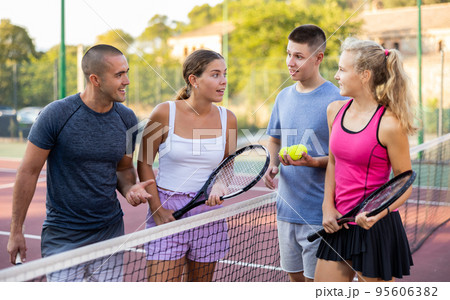 Friendly people chatting on outdoor tennis court 95606382