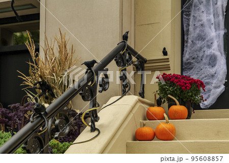 Assorted Halloween decorations guard the front steps of a house. Pumpkins on a porch. 95608857