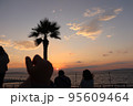 夕陽をの沈む海を眺める人たち 95609464