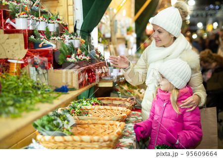 Young girl and her mother are buying Christmas ornamentals in the market outdoor Young girl and her mother are buying Christmas ornamentals in the market outdoor 95609664