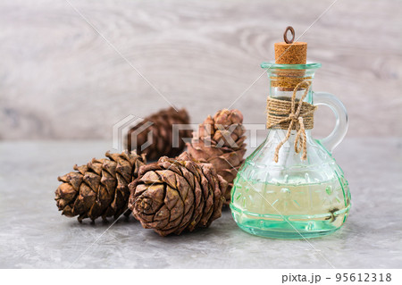 Cedar oil in a bottle and cedar cones on the table. Treatment of resin cedar. Alternative medicine 95612318