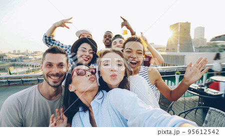 Point of view shot of happy friends taking selfe on roof at summer party laughing, posing and enjoying good company. Happiness, leisure and modern technology concept. 95612542