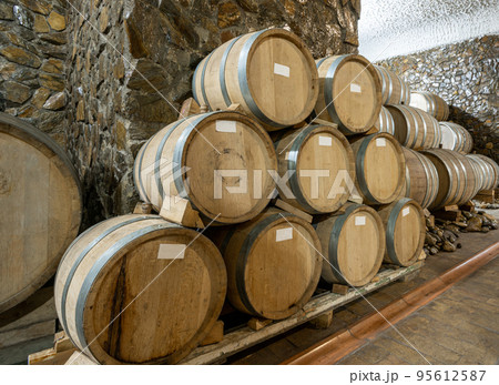 The wooden wine barrels in a wine factory The wooden wine barrels in a wine factory 95612587