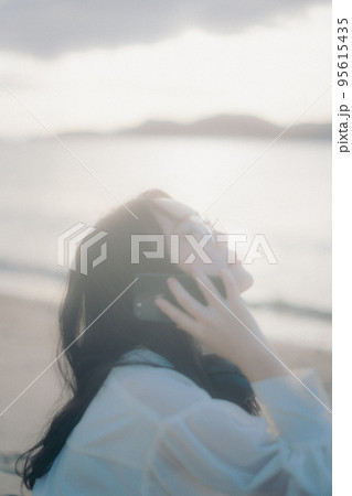 海辺で電話をかける女性の写真 海辺で電話をかける女性の写真 95615435