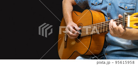 Guitarist playing acoustic guitar on black background, selective focus 95615958