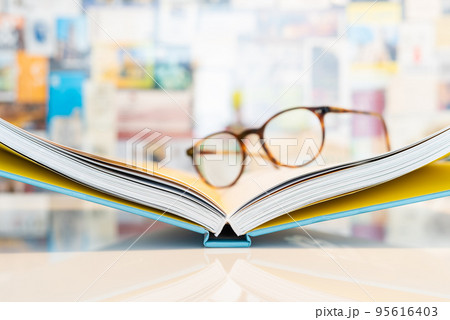 Open book with soft blurred reading glasses in background Open book with soft blurred reading glasses in background 95616403