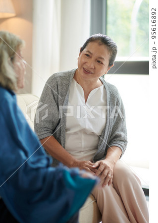 Elderly woman listening to friend telling news when visiting her at home Elderly woman listening to friend telling news when visiting her at home 95616892