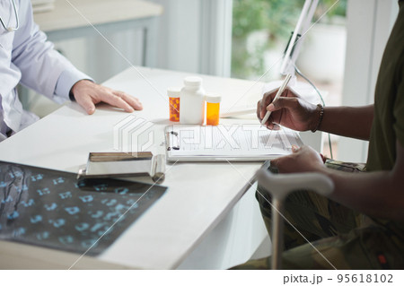 Cropped image of Black man filling form in medical office 95618102