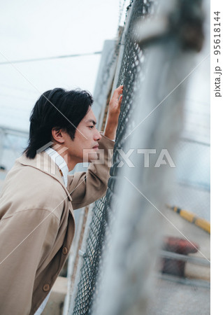 フェンスの前に立つ男性 95618144