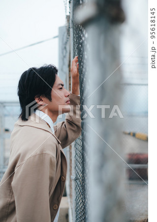 フェンスの前に立つ男性 95618145