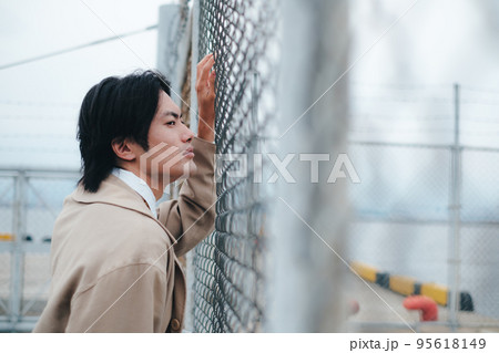 フェンスの前に立つ男性 95618149