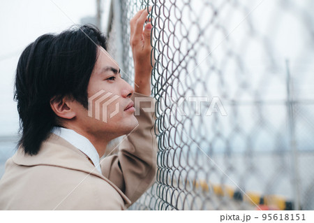 フェンスの前に立つ男性 95618151