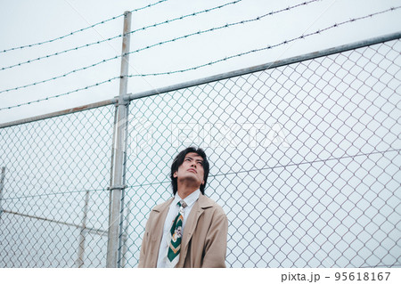 フェンスの前に立つ男性 95618167
