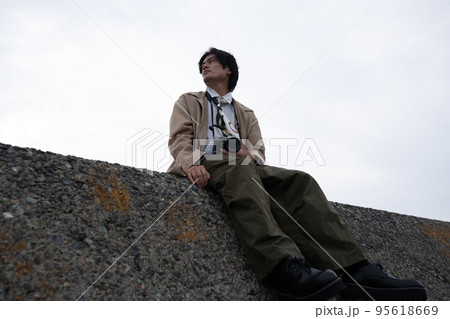 防波堤に座る男性 95618669