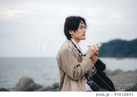 防波堤に座ってメモする男性 防波堤に座ってメモする男性 95618841