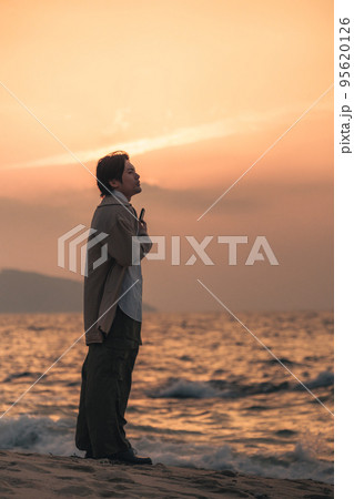 夕方に海辺でスマホを見る男性 夕方に海辺でスマホを見る男性 95620126