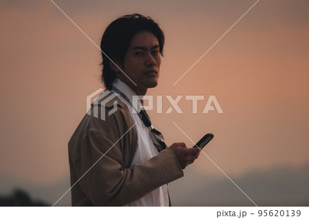 夕方に海辺でスマホを見る男性 夕方に海辺でスマホを見る男性 95620139