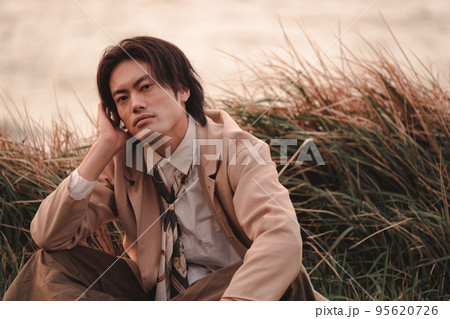 草むらに座って黄昏れる男性 95620726