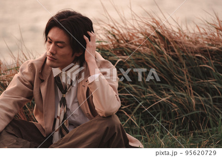草むらに座って黄昏れる男性 草むらに座って黄昏れる男性 95620729