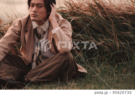 草むらに座って黄昏れる男性 草むらに座って黄昏れる男性 95620730
