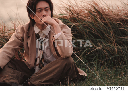 草むらに座って黄昏れる男性 草むらに座って黄昏れる男性 95620731
