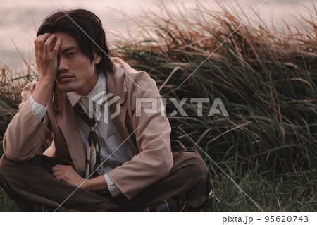 草むらに座って黄昏れる男性 草むらに座って黄昏れる男性 95620743