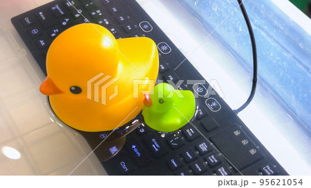 Yellow duck on the black keyboard background. Cute rubber ducks. Keyboard under the water. Yellow duck on the black keyboard background. Cute rubber ducks. Keyboard under the water. 95621054