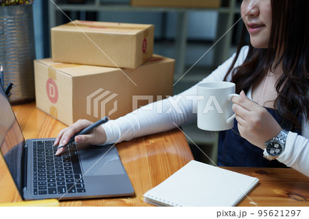 Starting small business entrepreneur of independent Asian woman smiling using computer laptop with cheerful success of online marketing package box items and SME delivery concept. 95621297