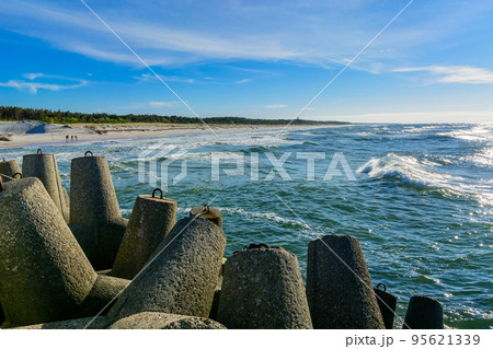 Wave breaker along the sea shore on the sand beach. 95621339