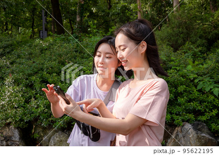 korean young women hiking and plogging_find directions using smartphone 95622195