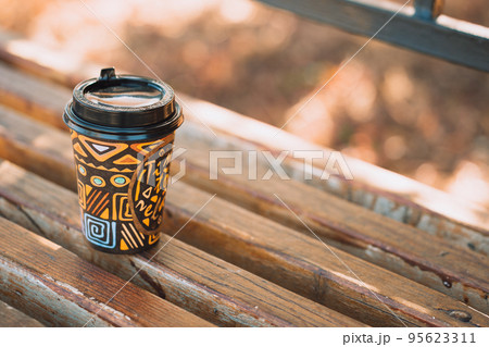 Glass of takeaway coffee on wooden bench 95623311