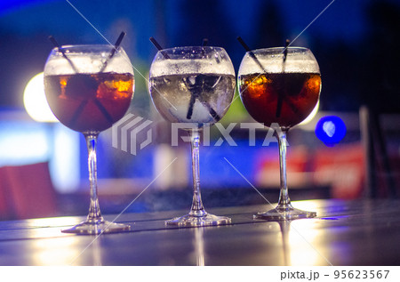Beautiful row line of different colored alcohol cocktails on a party, martini, vodka,and others on decorated catering bouquet table on open air event, picture with beautiful bokeh 95623567