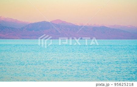 The surface of the water in the Issyk Kul mountain lake in Kyrgyzstan at sunset.Pastel and soft tones of water and sky against the background of mountains. 95625218