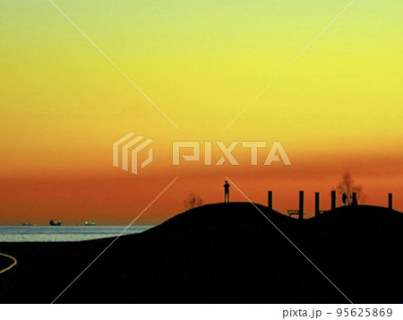夕焼け背景に浮かぶ人のシルエット 95625869