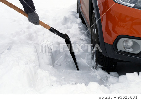 Man with shovel clears snow around car in parking lot in winter after snowfall. Shovel in hand. Winter problems of car drivers. Man with shovel clears snow around car in parking lot in winter after snowfall. Shovel in hand. Winter problems of car drivers. 95625881