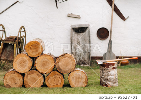 Round firewood is stacked near the shed for subsequent cutting Round firewood is stacked near the shed for subsequent cutting 95627701
