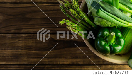 Close-up of fresh asparagus, green bell pepper, cucumber, chinese cabbage in bowl on wooden table 95627731