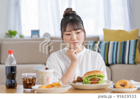チートデイ　ジャンクフードを前に悩む若い女性 95629533