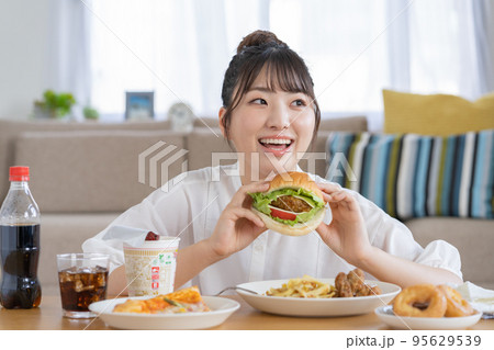 チートデイ ジャンクフードを前に微笑む若い女性 チートデイ ジャンクフードを前に微笑む若い女性 95629539