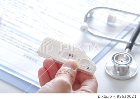 抗体検査キットを見て、病気の診察をする医師 95630021