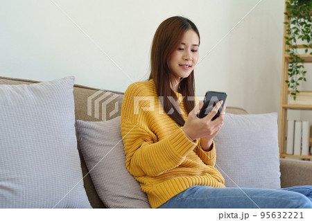 woman sitting on sofa at home ready to use mobile phone. 95632221