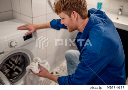Man putting unfresh clolthes into the washing machine Man putting unfresh clolthes into the washing machine 95634933