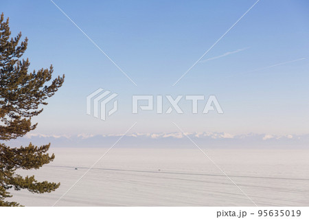 Frozen Lake covered with snow. Snow capped mountains on the horizon. 95635019