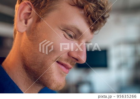 Headshot of a ginger young man looking down and smiling 95635266