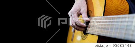 Guitarist playing acoustic guitar on black background, selective focus. Long wide banner, copy space Guitarist playing acoustic guitar on black background, selective focus. Long wide banner, copy space 95635448