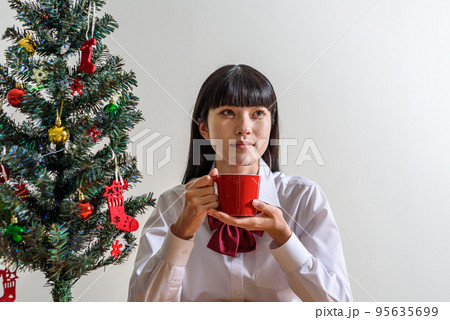 クリスマスを楽しみに待つ女子高校生　マグカップで飲み物を飲んで温まる 95635699