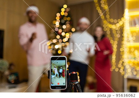 funny friends record reels stories front smartphone camera for social networks during New Year holidays party Christmas Eve celebration. Having fun dancing look pose at camera at home guys having fun 95636062